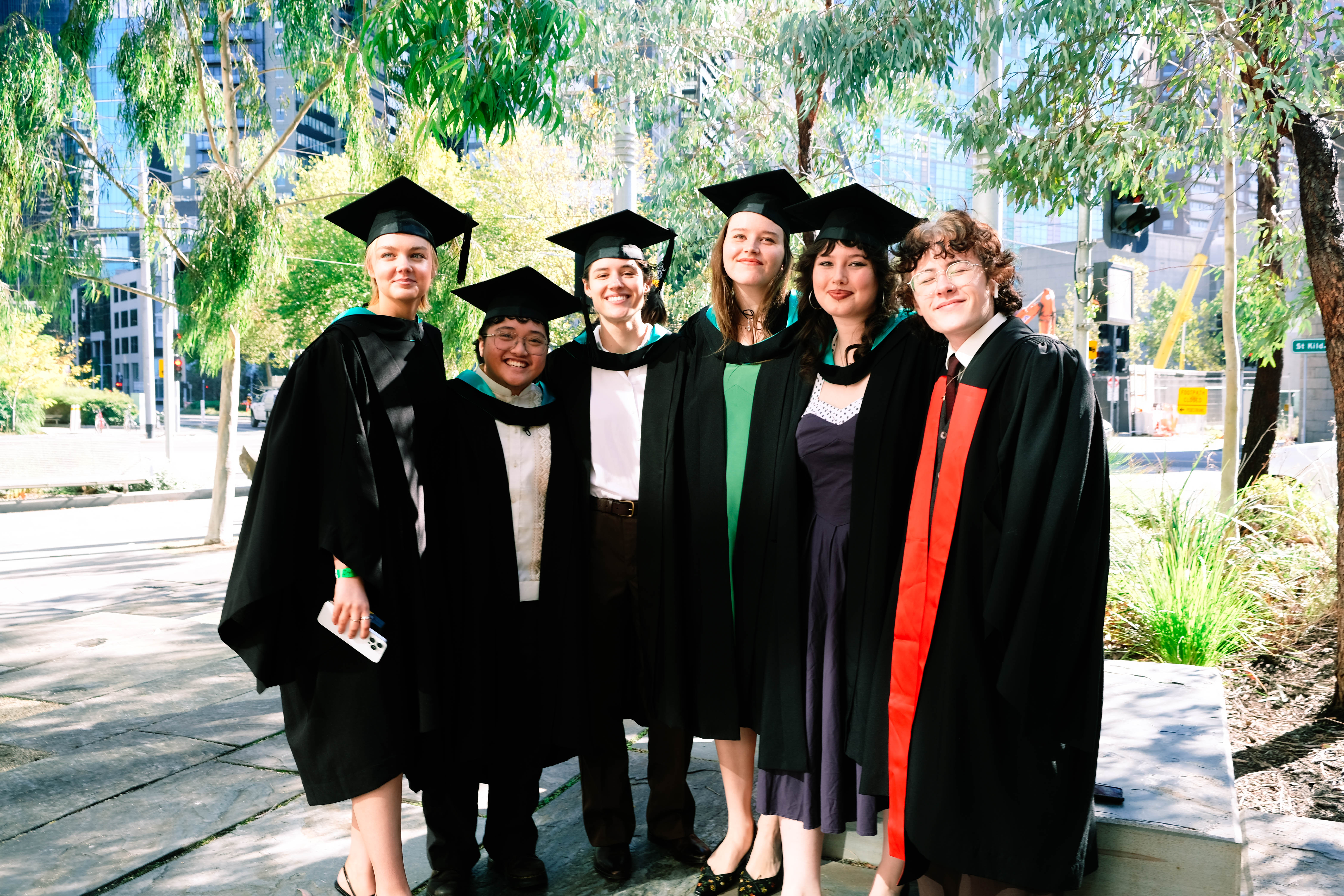 A group of collarts graduates posing in their graduation robes and smiling