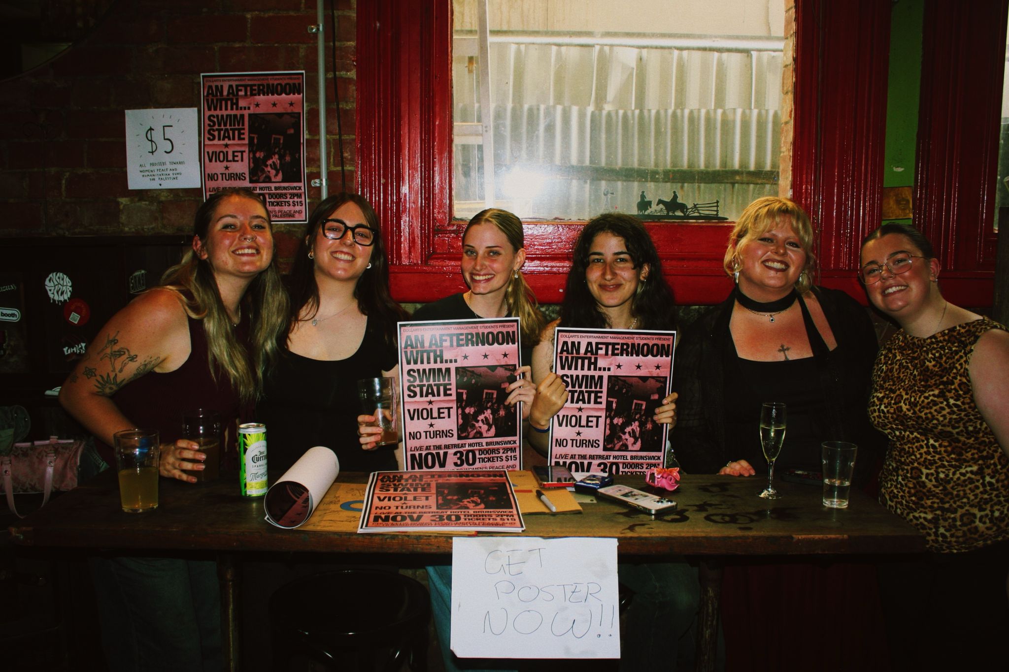 Group of Collarts entertainment management students smiling and sitting, holding up their event posters
