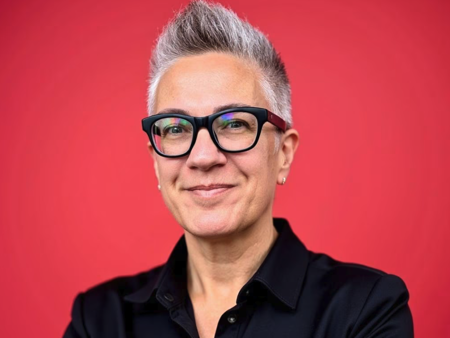 Collarts CEO Sam Jacob headshot, smiling against a read background