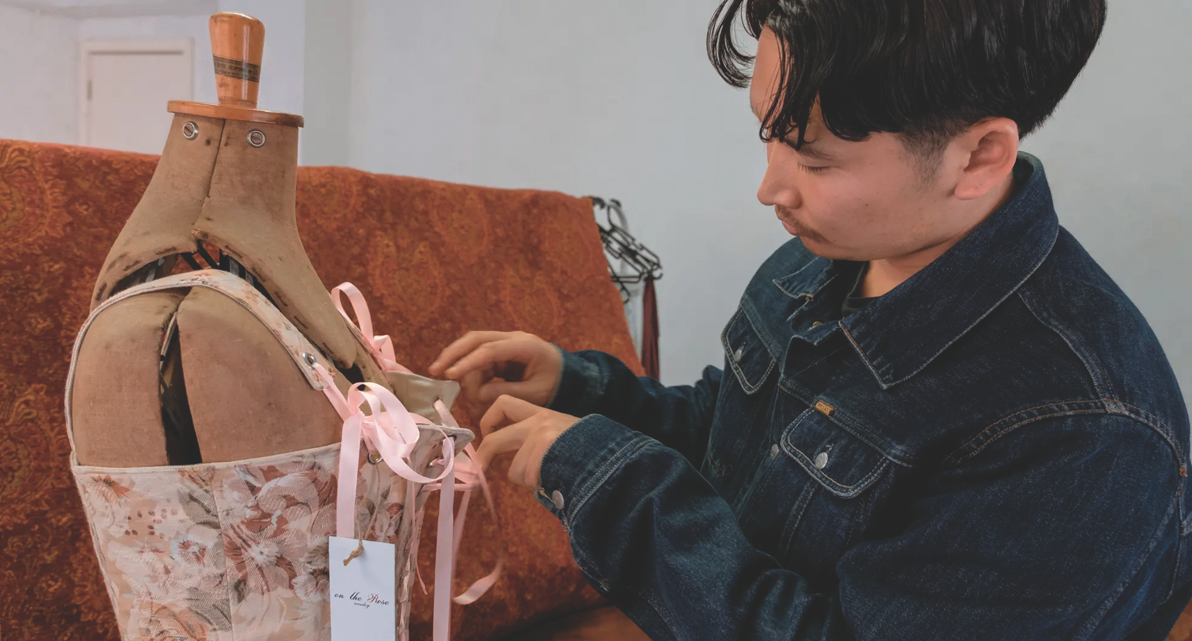 Collarts fashion student adjusting his corset on a mannequin 