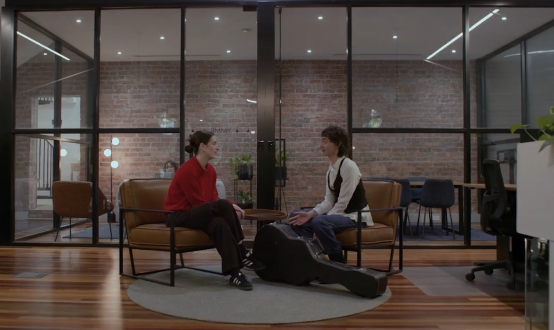 Collarts entertainment management student sitting across from and speaking with a music artist with a guitar case at his feet