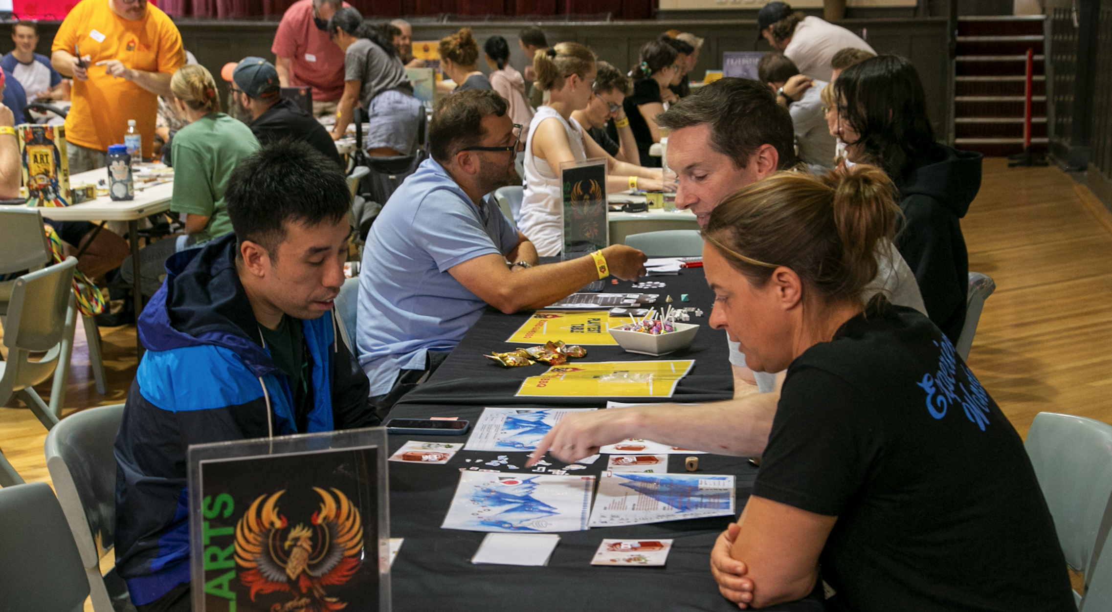 A group of three people sitting at a table and playing a table top game. 