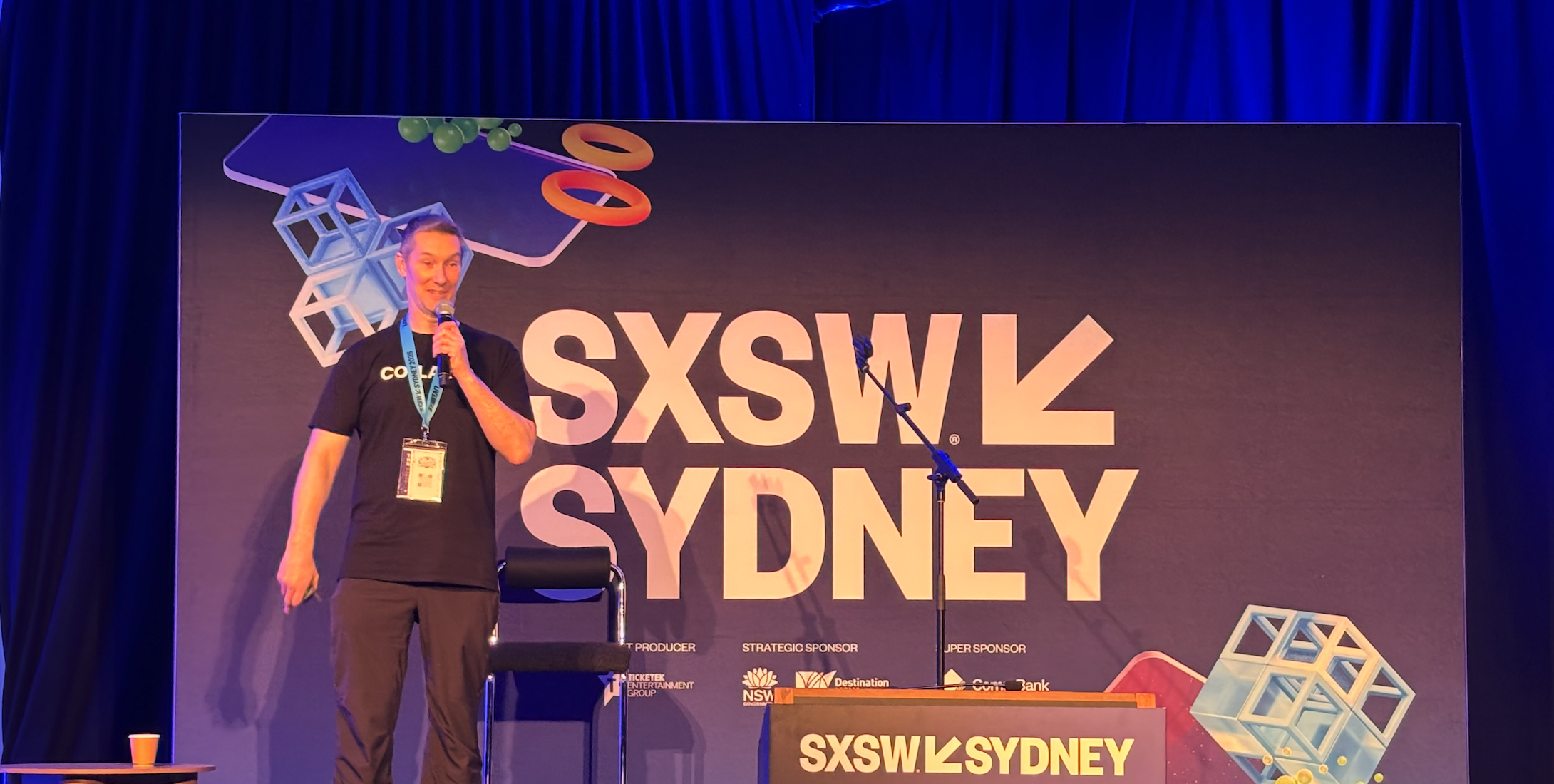 Collarts game design program leader Tim Westhaven speaking into a microphone while standing in front of a sign that reads SXSW SYDNEY
