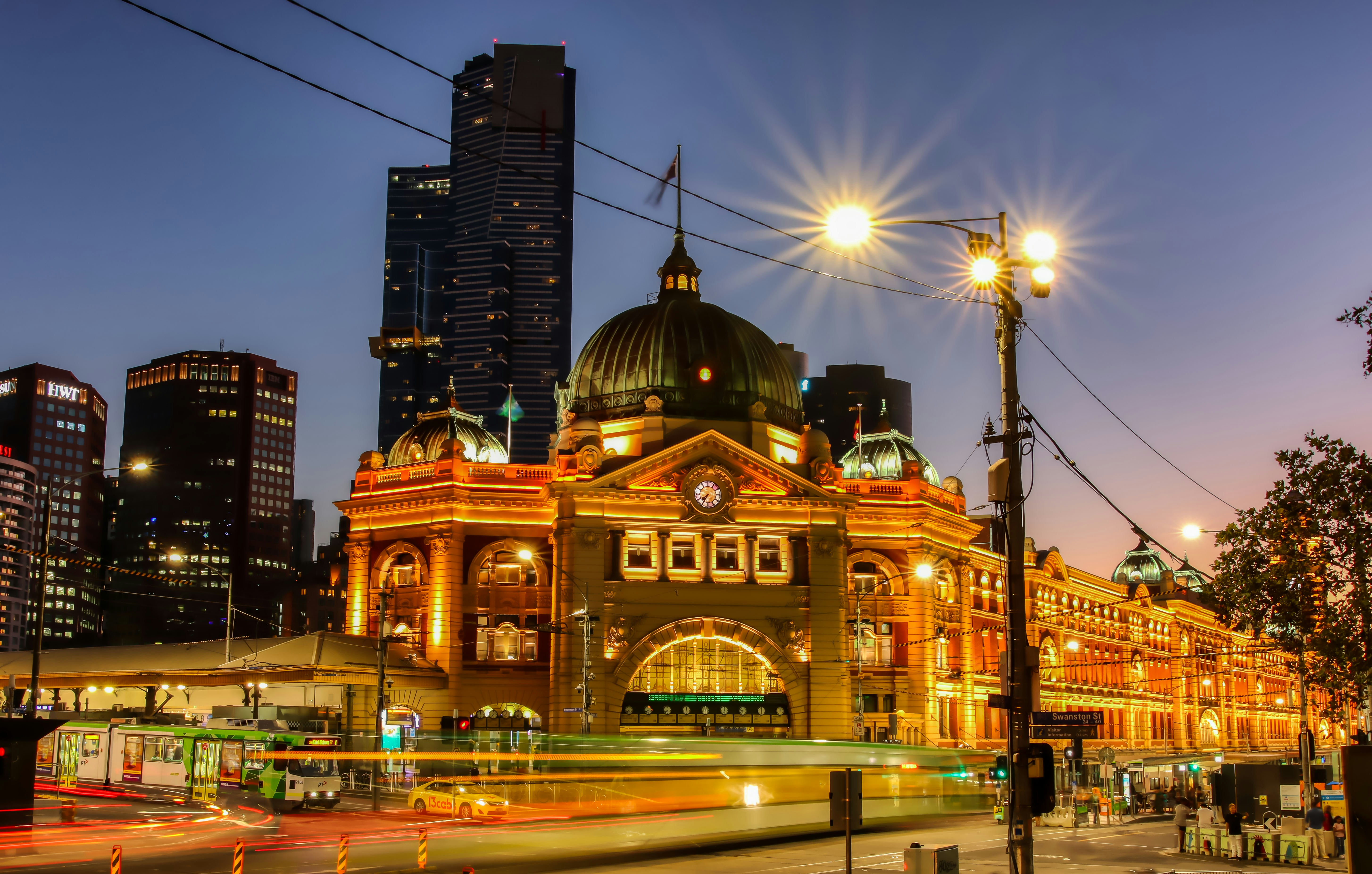 Flinders street station lit up at night with trams passing by in Melbourne CBD