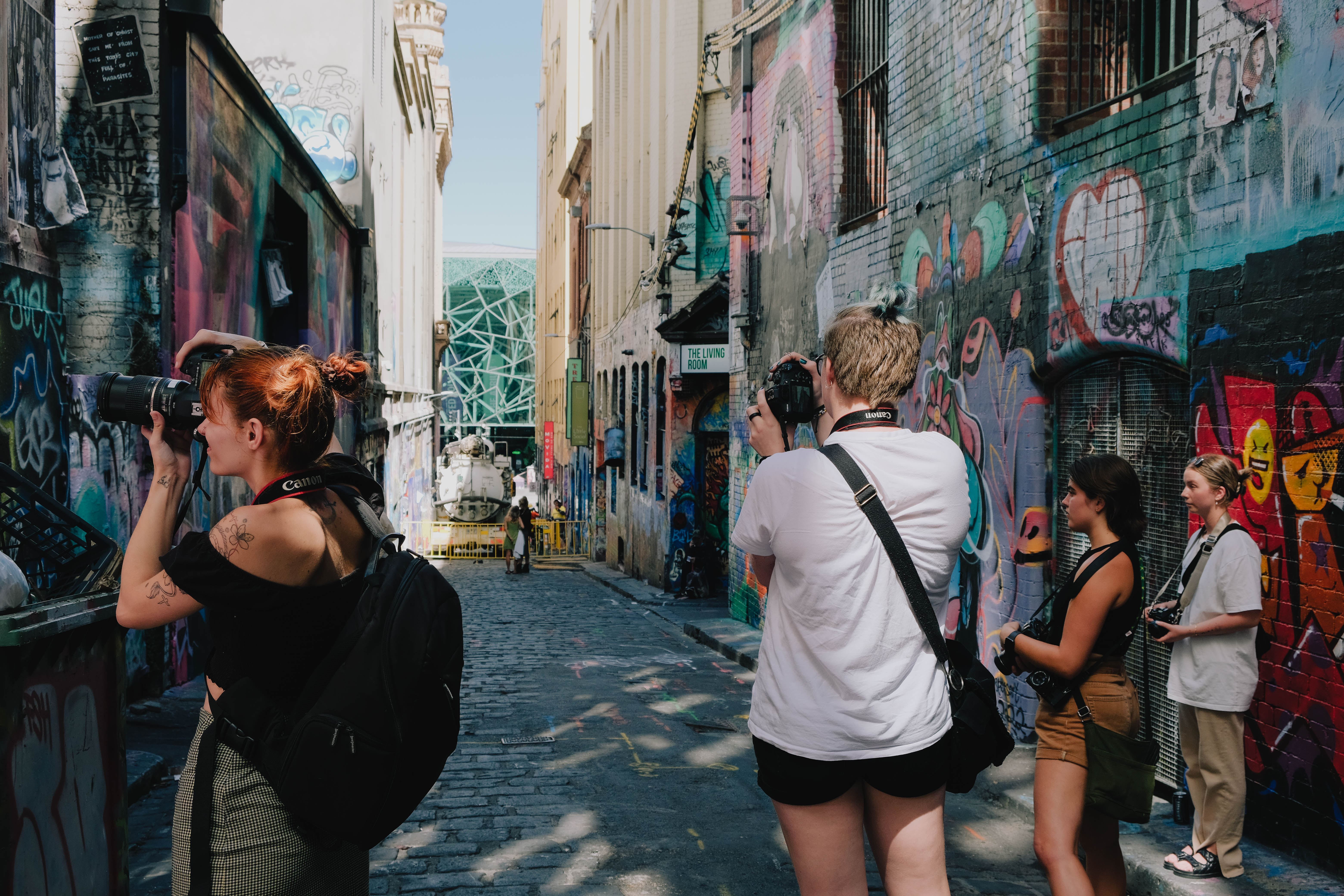 Four Collarts photography students pointing cameras at graffiti art in Melbourne alleyway