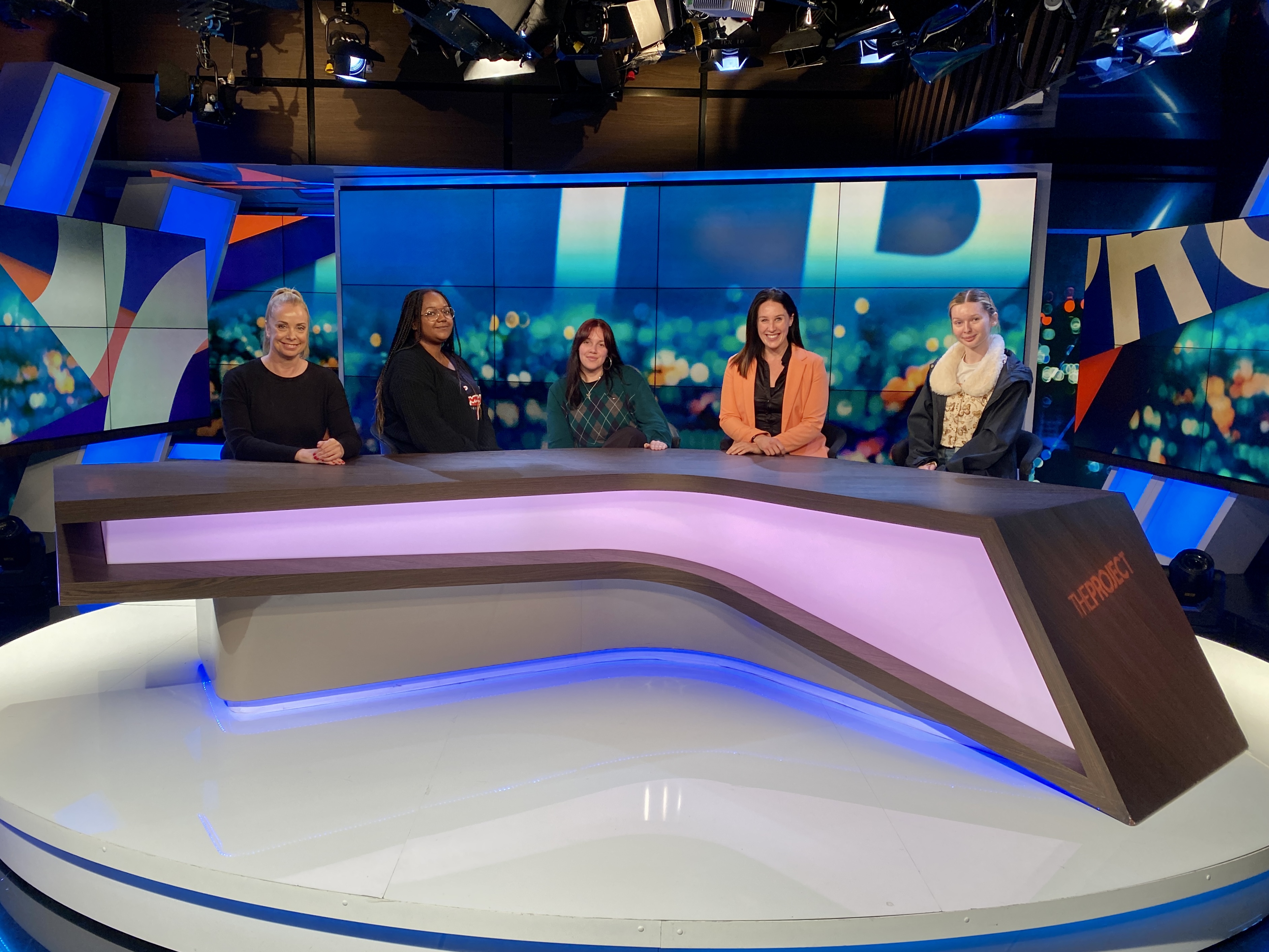 Group of Collarts journalism students smiling and sitting on a panel on set filming for The Project TV Show
