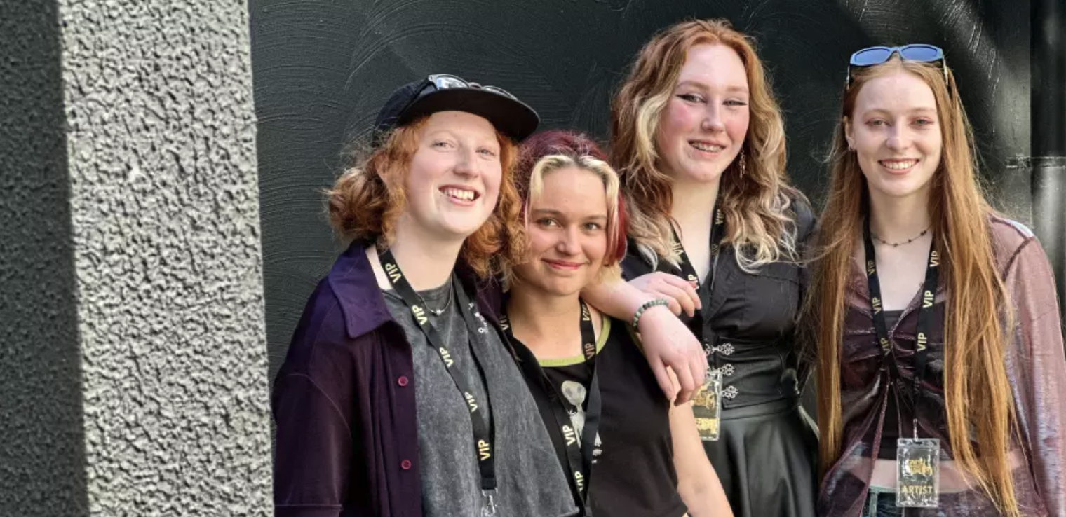 Collarts student smiling and posing for a photo with her band members 