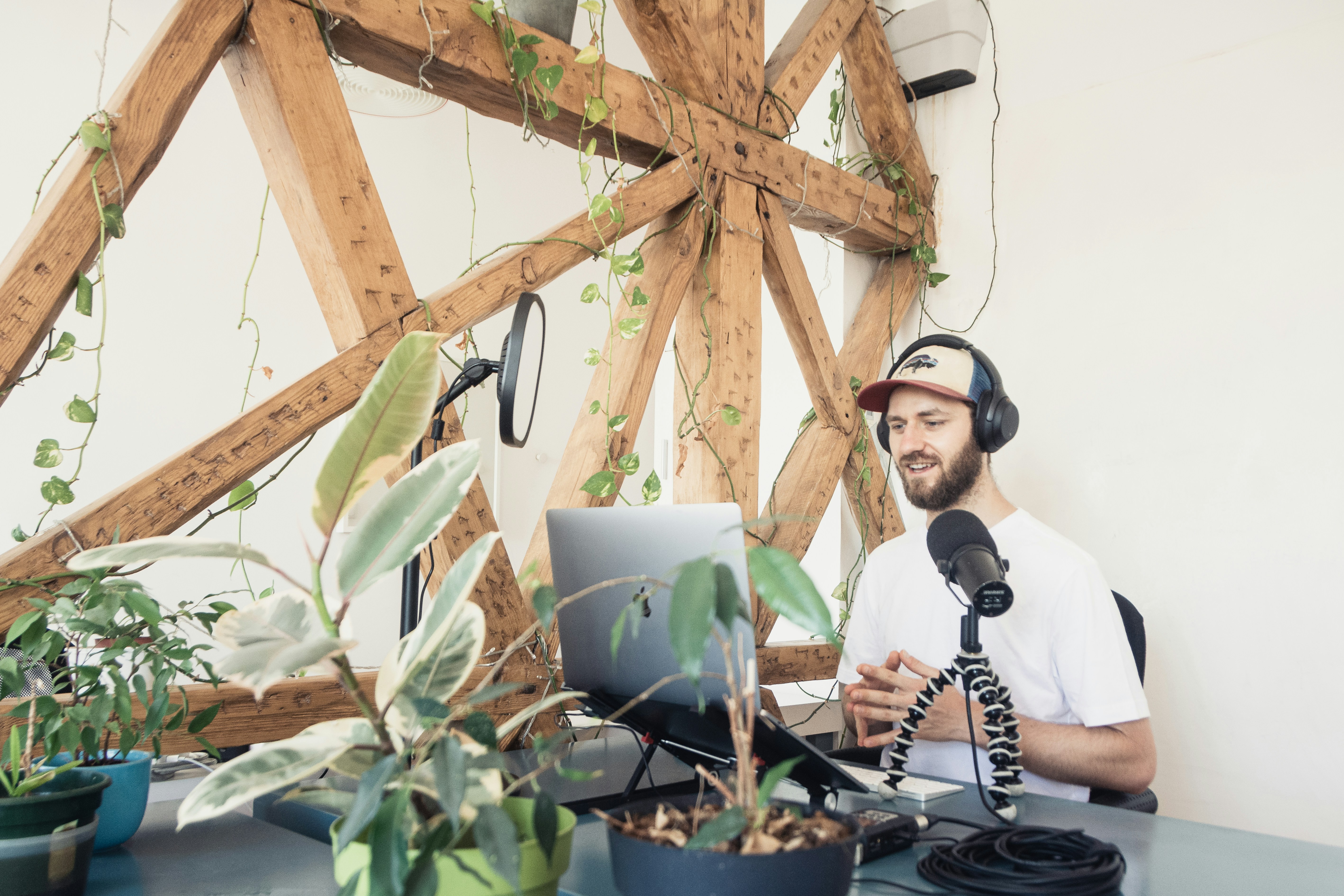 A person with headphones on sitting at a desk with his laptop and headphones on, recording content 