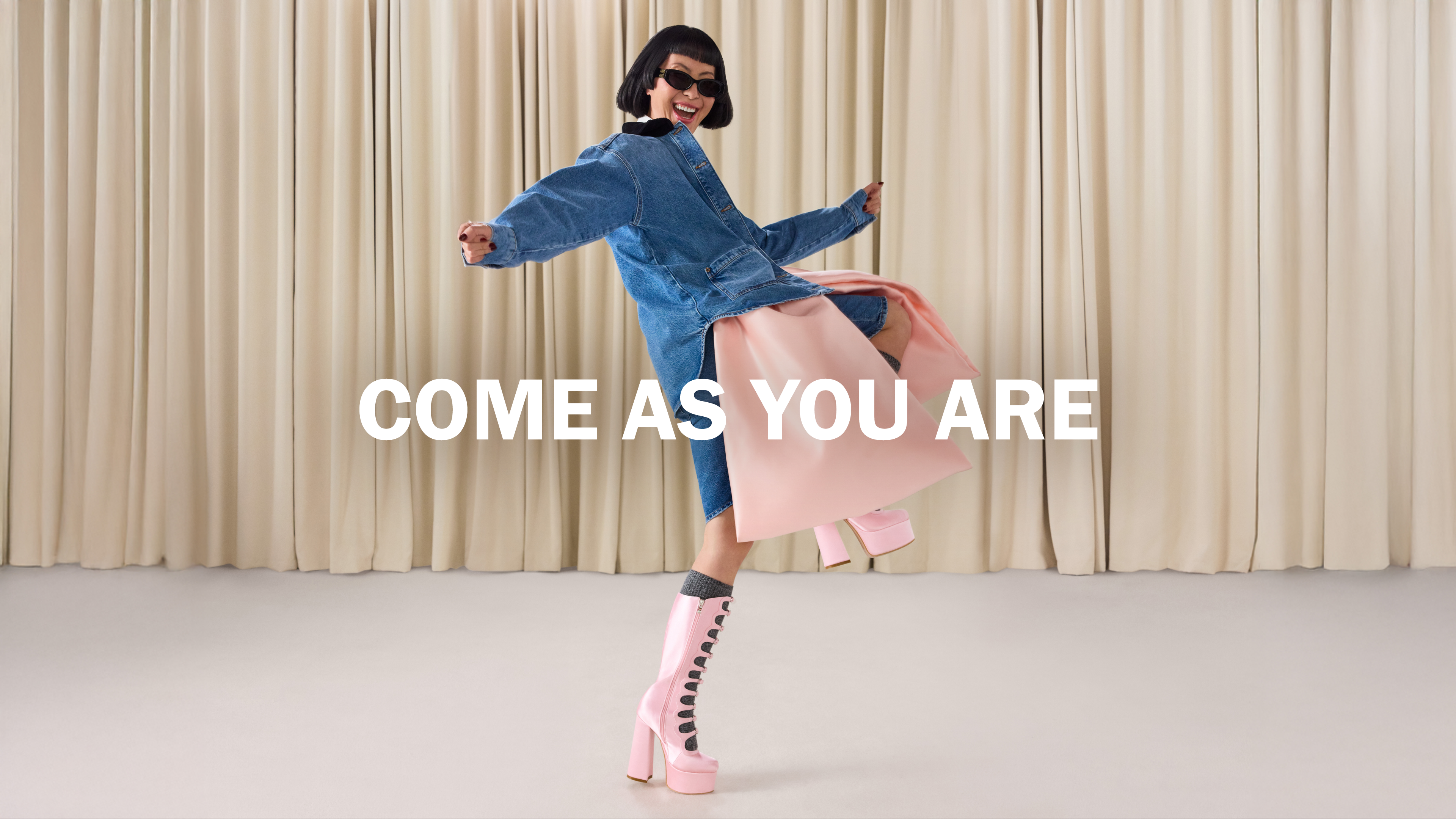 Model smiling and kicking leg with text overlaid saying 'come as you are'